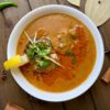 A bowl of Nihari, a tender portion of beef slow cooked in thick aromatic gravy, garnished with fresh herbs.